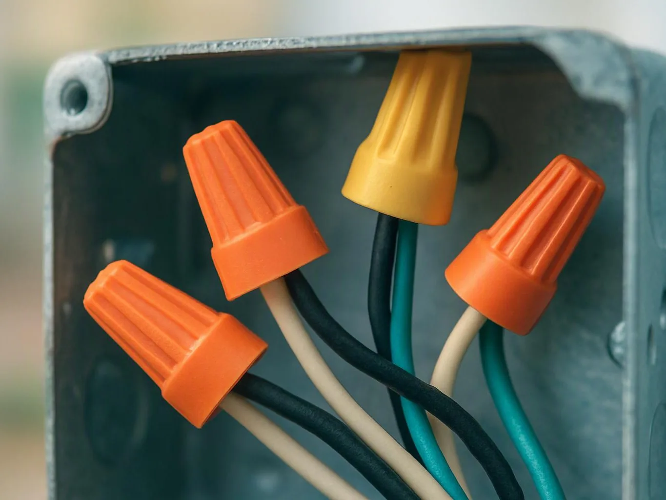 Colored wire nuts connect several electrical wires inside a metal junction box
